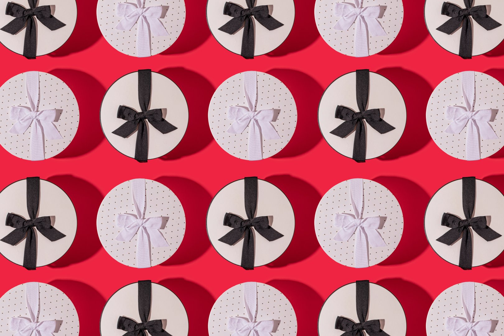 Rows of small, round gift boxes each with a black or white ribbon.
